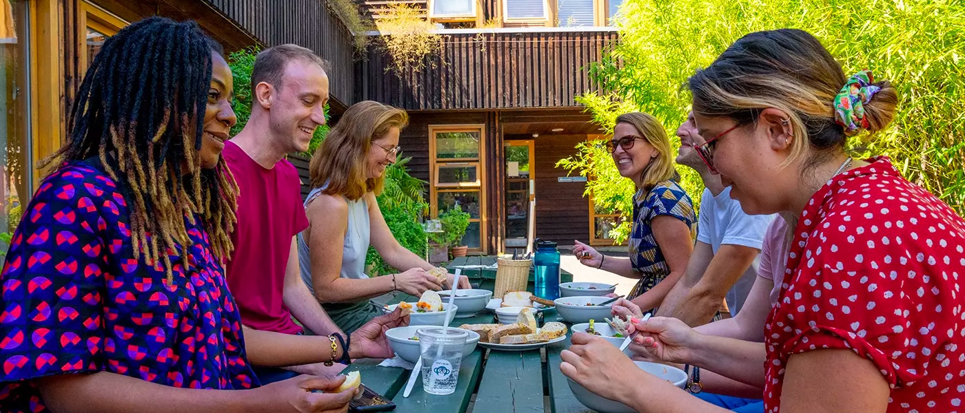 six people around a bench eating together